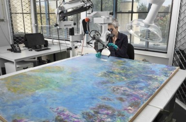 Gemeentemuseum restorer Ruth Hoppe examines Monet's Wisteria painting. Image courtesy Gemeentemuseum.